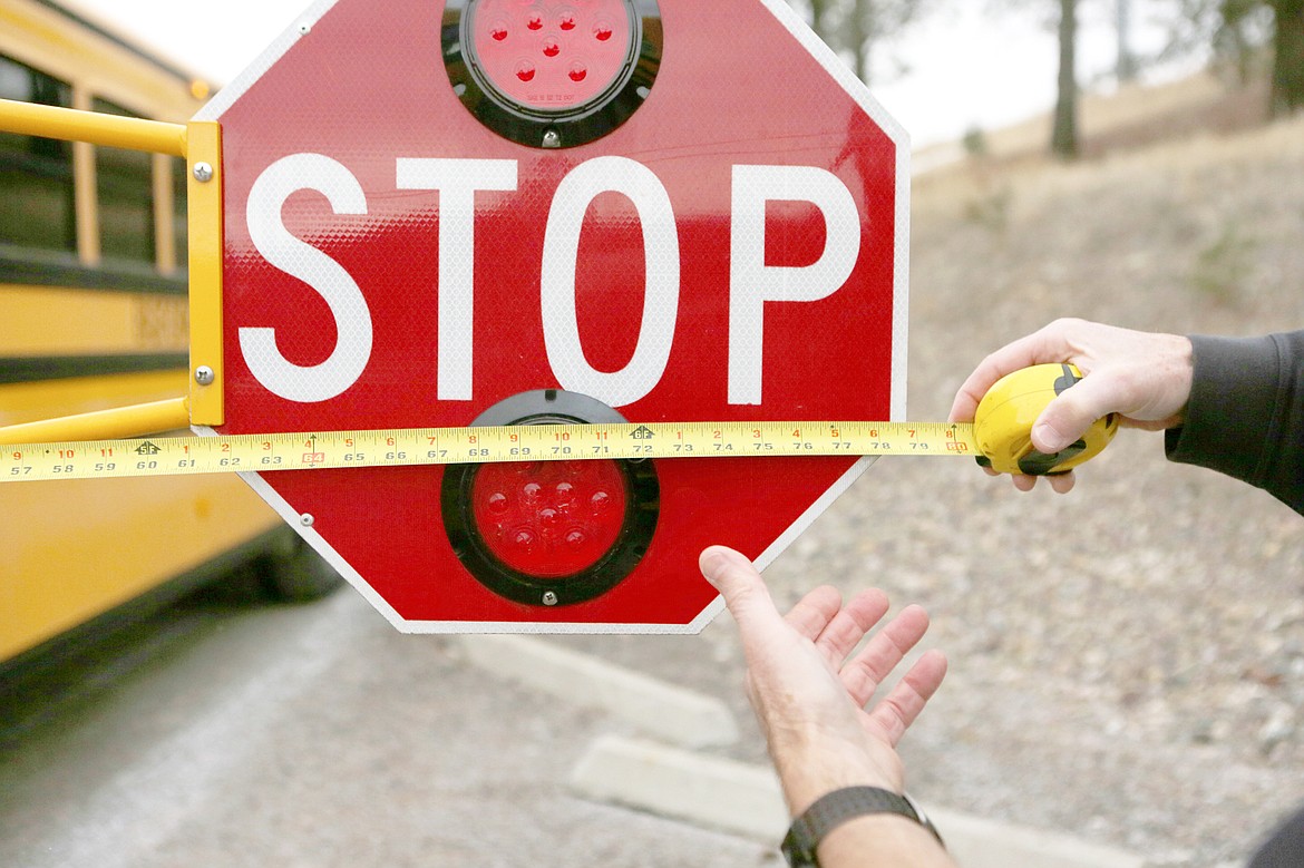 Rob Tracy measures the length of the new school bus stop arm, which is over six feet compared to the original equipment which measured about two feet long.