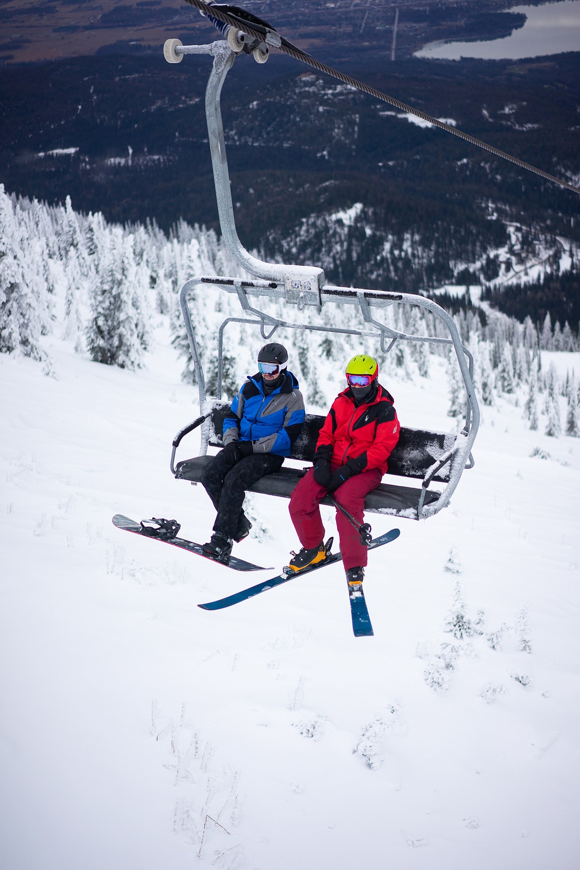 A snowboarder and a skier head up Chair 1 on opening day.  (Daniel McKay/Whitefish Pilot)