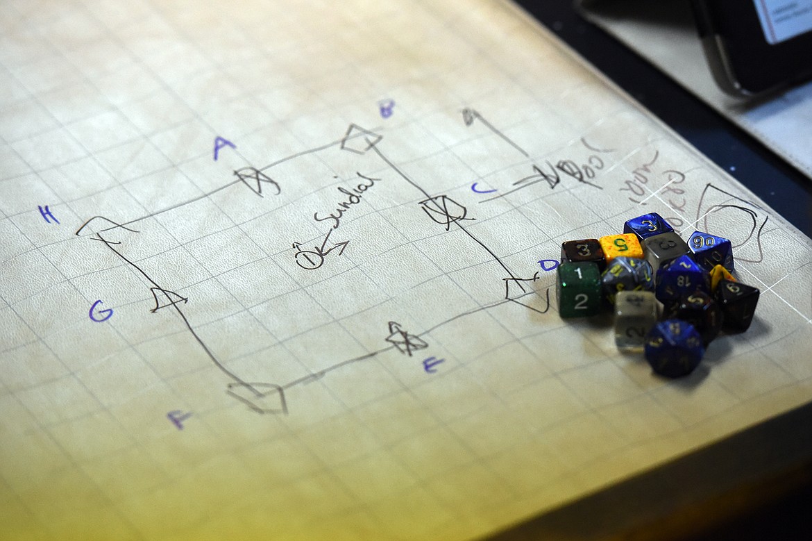 Directions for entering a portal are drawn on a playing grid next to a set of polyhedral dice during a game of Dungeons &amp; Dragons.