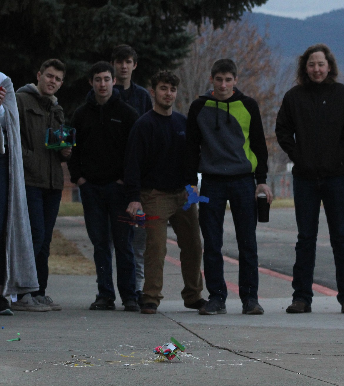 FROM LEFT to right, are Nathan McNulty, Andrew Harmon, Kade Pardee, Mason Gannarelli, Conrad Vanderwall, Wiley Scribner, watch one of the devices as it fails to protect an egg as it landed on the concrete. (John Dowd/Clark Fork Valley Press)
