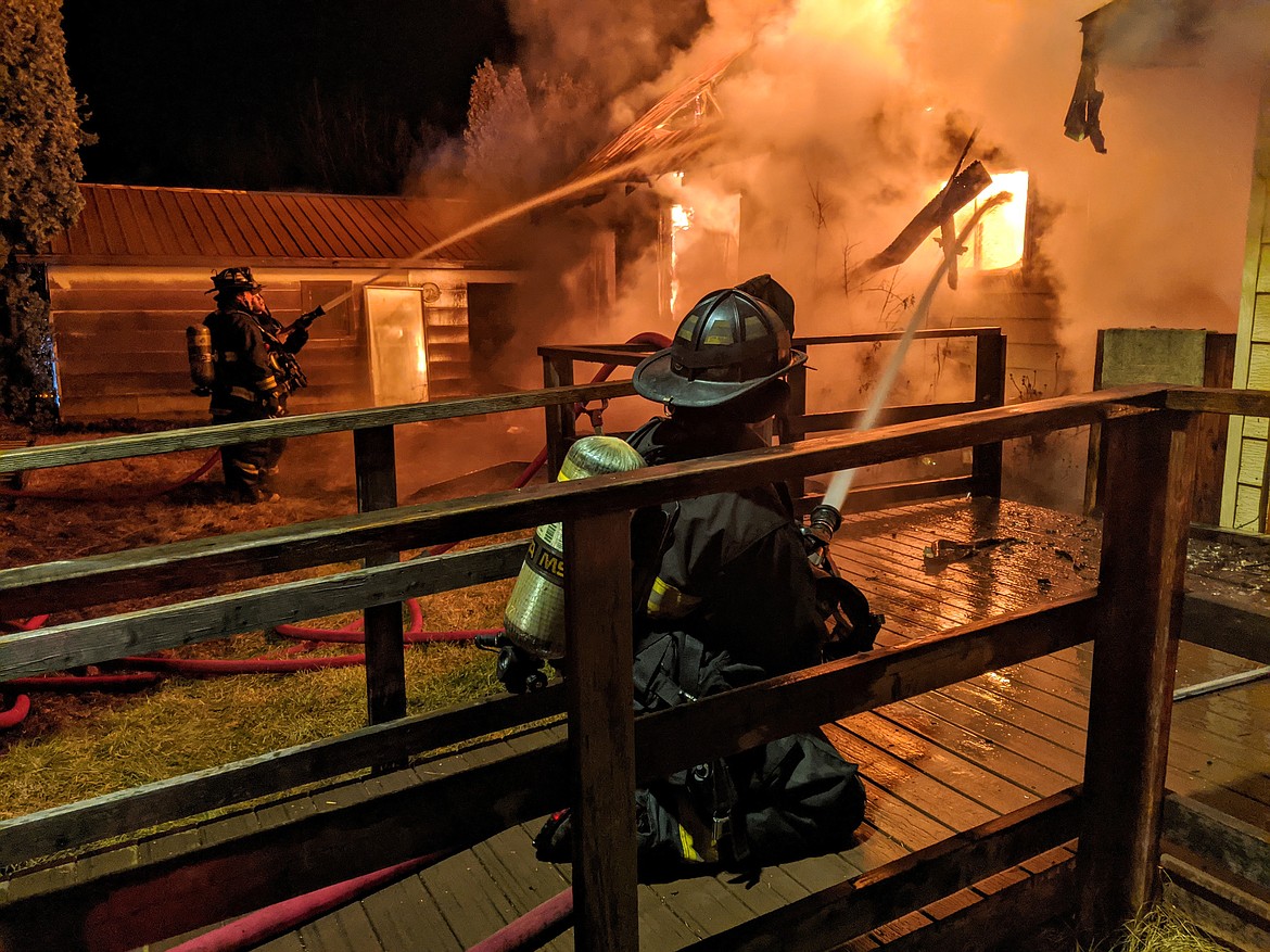 Firefighters Rotchford, Myles and Waites hose down the burning building.