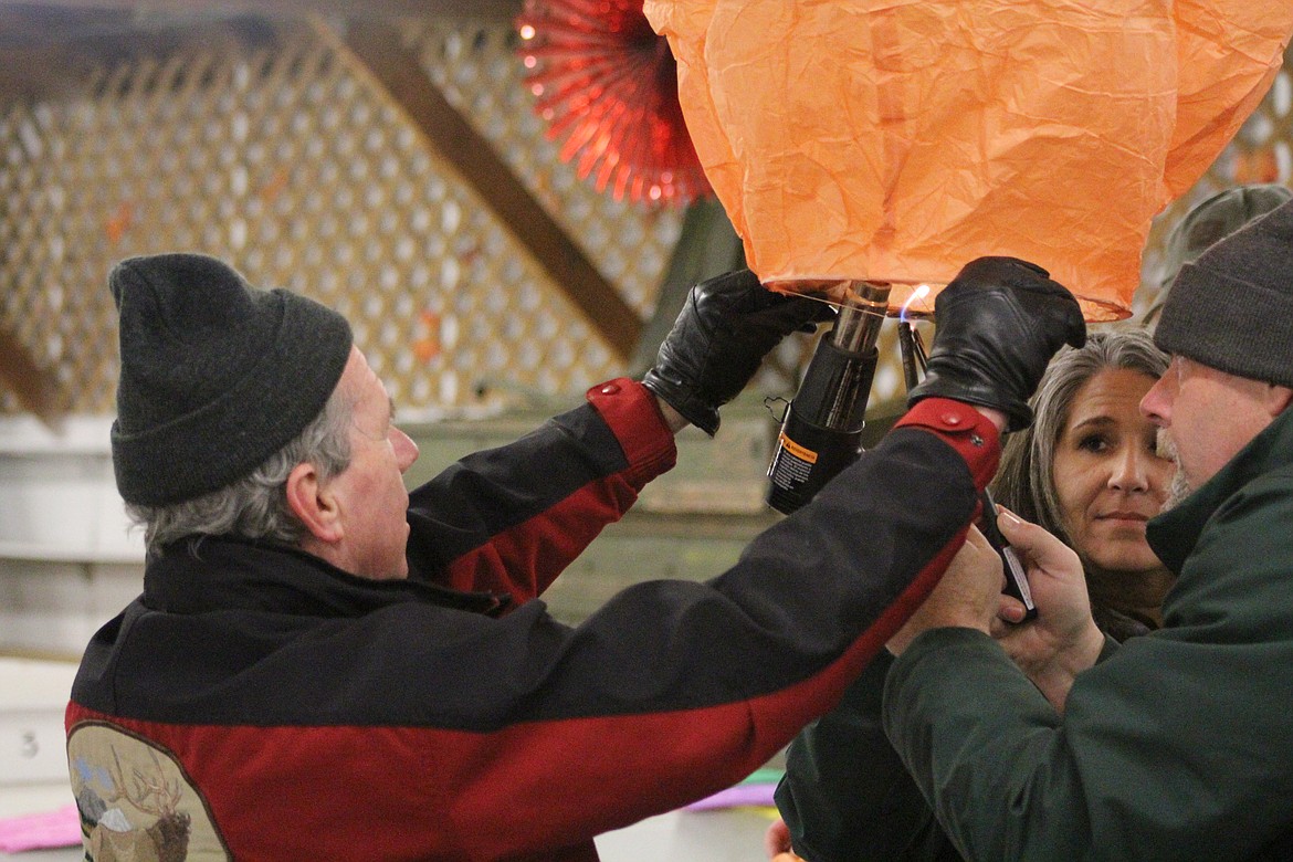 JOHN CLARK, holding the lantern, is assisted by Shelley and Michael Bertrand, inflating and lighting one of many wishing lanterns to honor and remember those taken by cancer Saturday night. (John Dowd/ Clark Fork Valley Press)