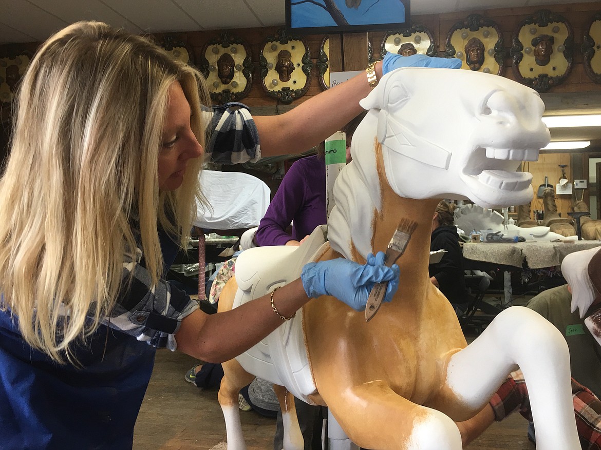 Carousel of Smiles volunteer Sydney Icardo paints the body of one of the ponies.