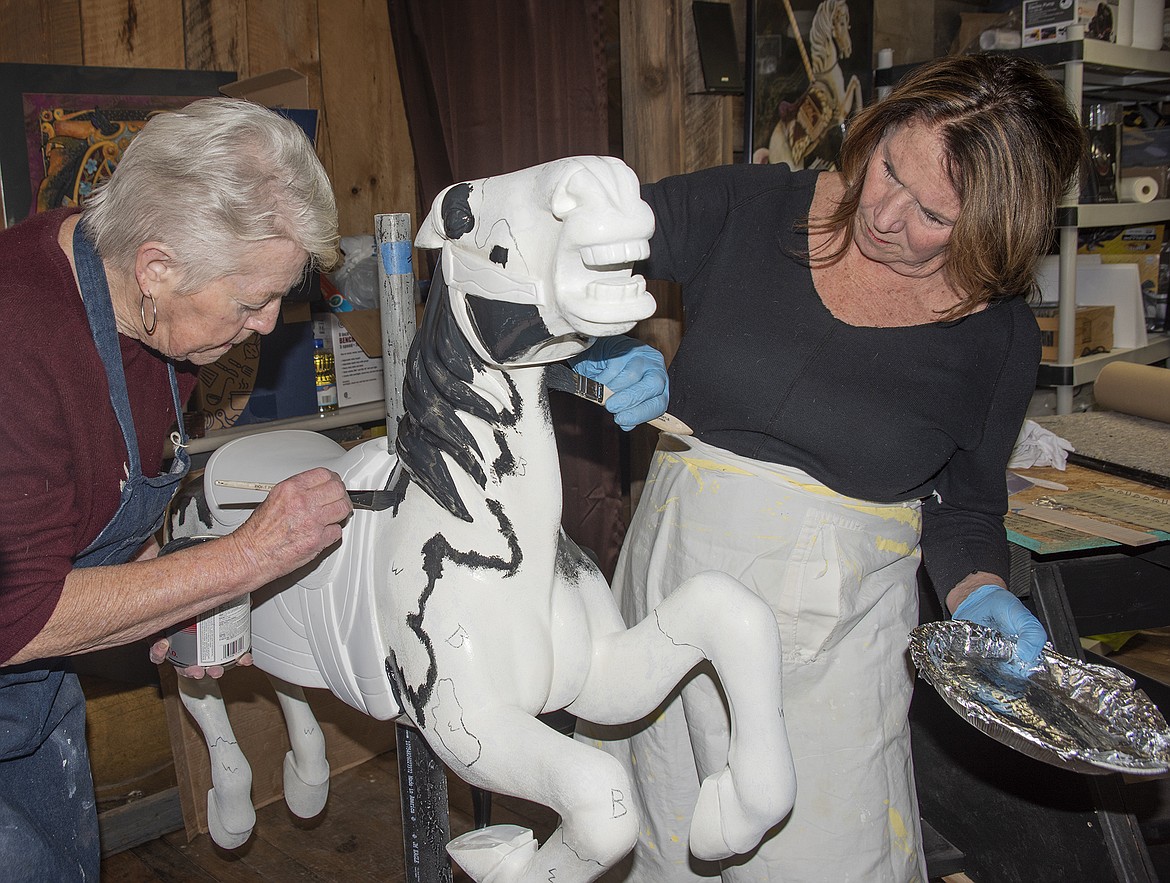 Carousel of Smiles volunteers Gabe Gabel and Mary Day start on painting a pinto pony.