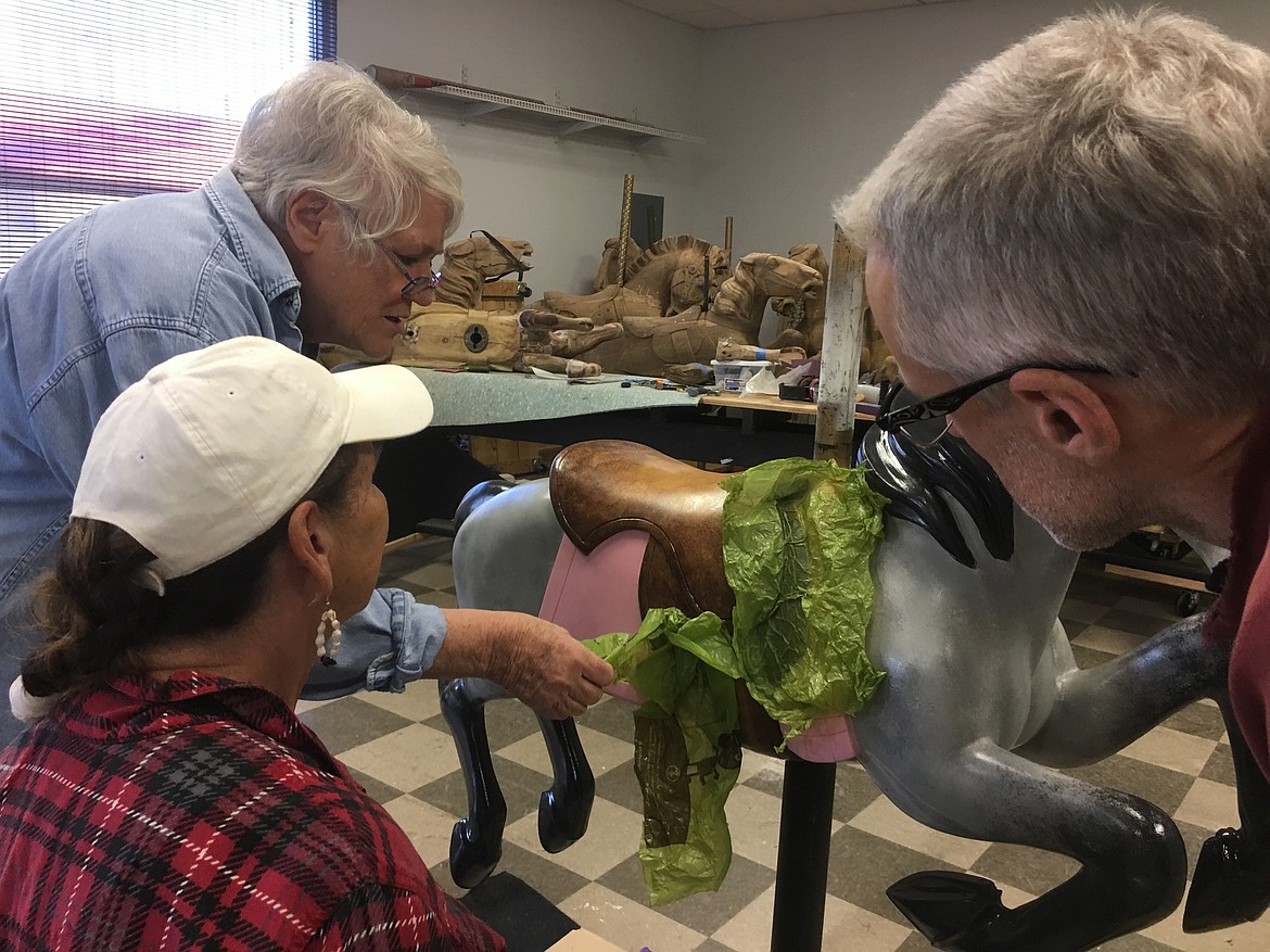 (Photo courtesy CLAY HUTCHISON)
Carousel of Smiles volunteer Bette Largent demonstrates a painting technique to using plastic bags to give the pony's saddle its leather-like look.