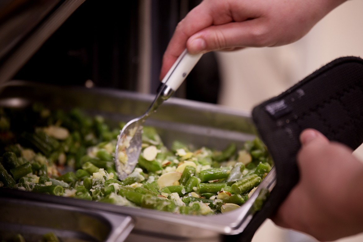 A student does a final check and stir of a vegetable dish for the Kalispell Chamber luncheon.