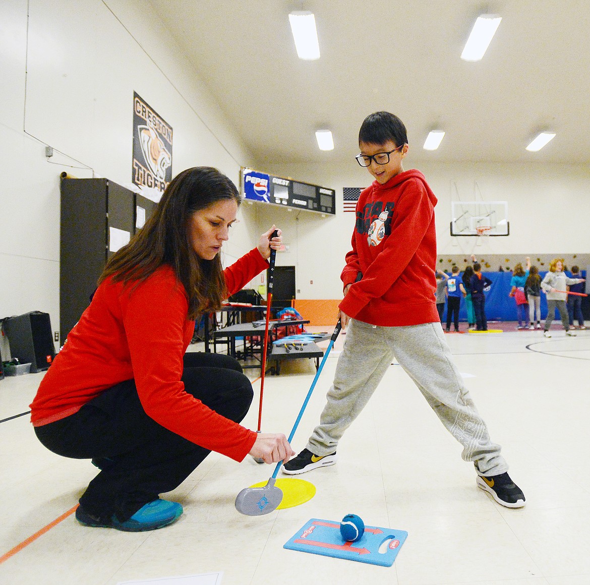 Teacher Teresa Mumm works with fourth-grader Elijah Goodson during a golf program at Creston School on Wednesday. (Casey Kreider/Daily Inter Lake)