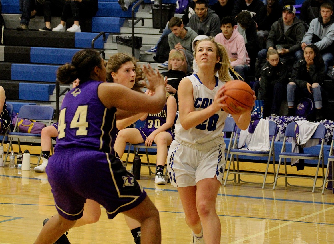 Casey McCarthy/The Sun Tribune Jaryn Madsen drives in for the layup against a pair of Columbia players on Tuesday night at Warden High School.