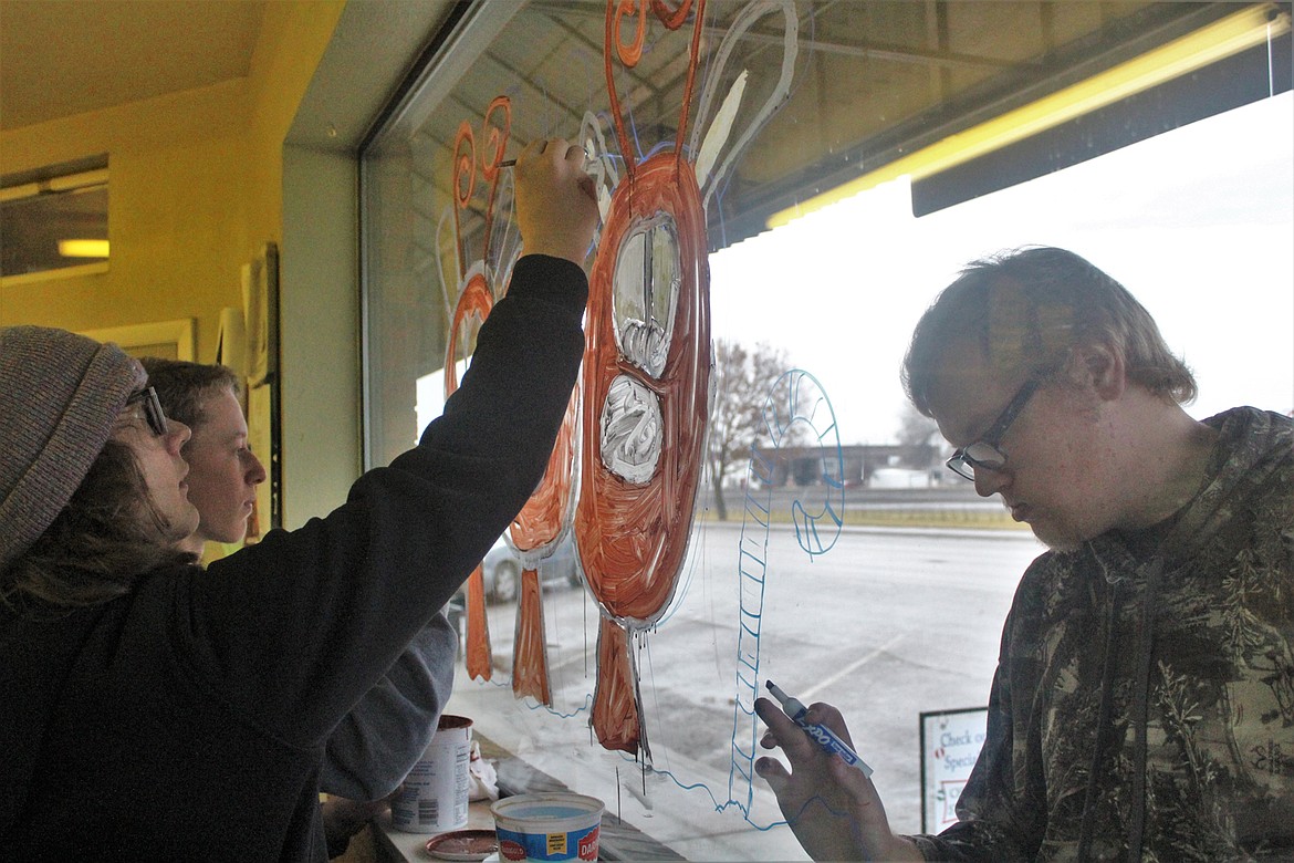 Parker Flock, Maxwell Starika and Mason Elliott painting the windows of the Printery last Thursday morning. (John Dowd/Clark Fork Valley Press)