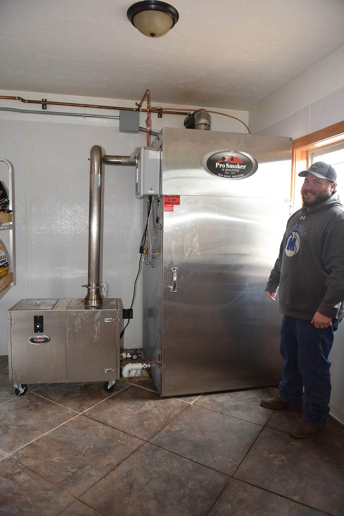 Max Nash shows off the giant smoker at his new business, Montana Marbled Meats. (Carolyn Hidy/Lake County Leader)