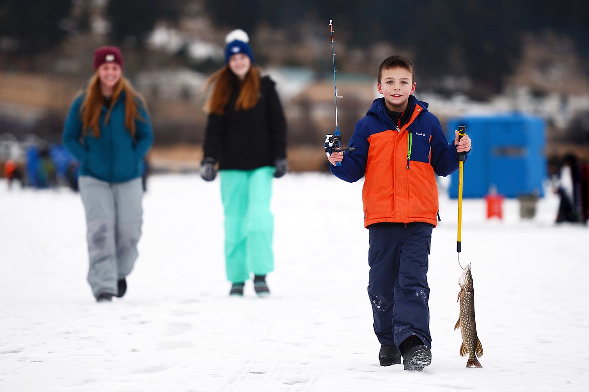 Jackson Brisendine, of Kalispell, carries a northern pike he caught and a new ice fishing rod from the Flathead Chapter of Walleyes Unlimited at the 49th annual Sunriser Lions ice fishing derby at Smith Lake on Saturday. The Flathead Chapter of Walleyes Unlimited donated 100 rod and reel sets to be given away at the derby, which serves as a fundraiser for the Sunriser's family fishing pond programs. The Lions also served up a variety of burgers, hot dogs, chili and hot drinks for attendees. (Casey Kreider/Daily Inter Lake)