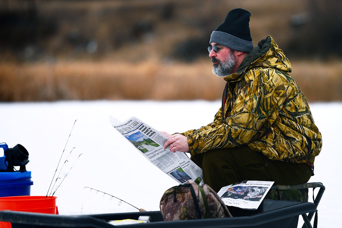 Tyler Corey, of Kalispell, reads the Daily Inter Lake while waiting for a bite at the 49th annual Sunriser Lions ice fishing derby at Smith Lake on Saturday. (Casey Kreider/Daily Inter Lake)