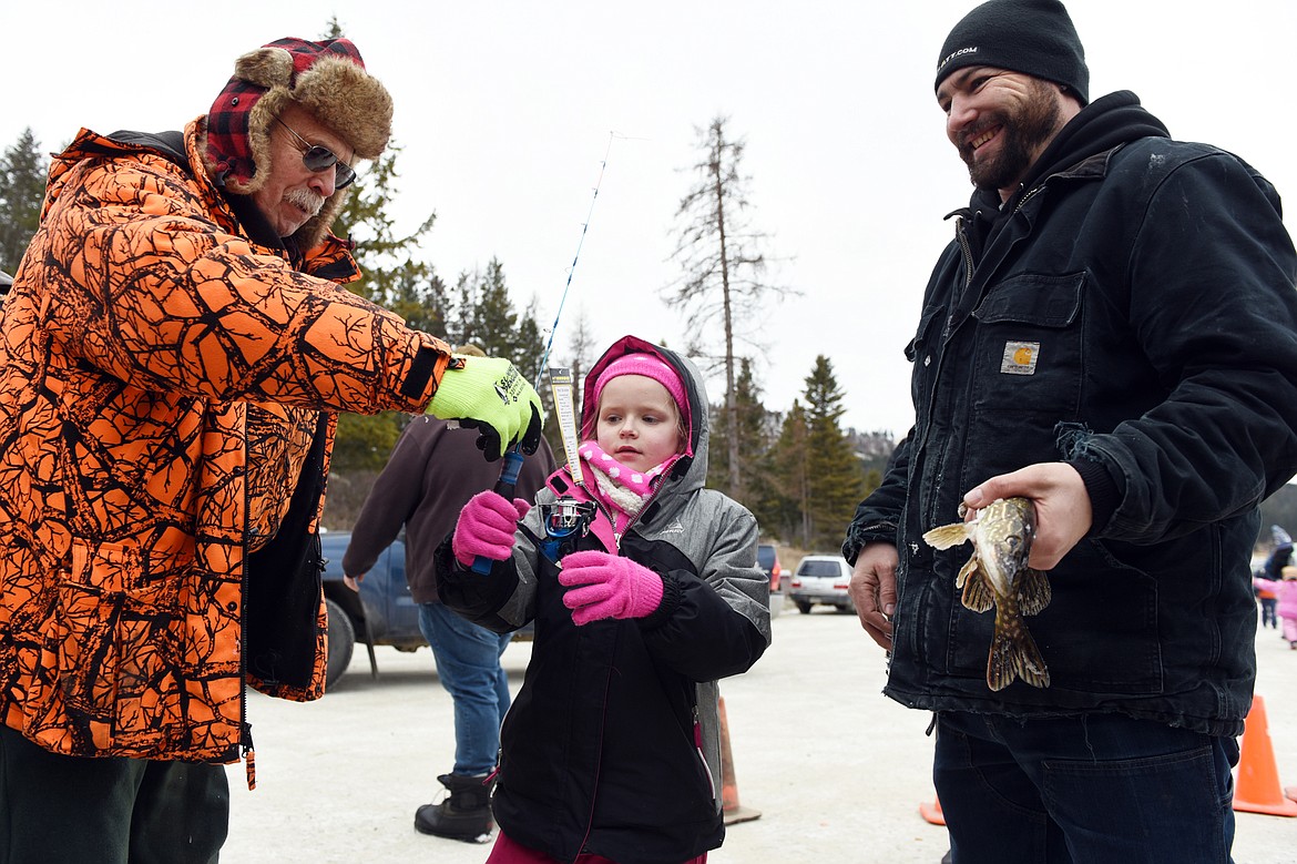 Atalie Benton, of Kalispell, receives a new ice fishing rod and reel set from Warren Illi, left, with the Flathead Chapter of Walleyes Unlimited, after getting her northern pike weighed with her father, Andy Kitzmiller, at the 49th annual Sunriser Lions ice fishing derby at Smith Lake on Saturday. The Flathead Chapter of Walleyes Unlimited donated 100 rod and reel sets to be given away at the derby, which serves as a fundraiser for the Sunriser's family fishing pond programs. The Lions also served up a variety of burgers, hot dogs, chili and hot drinks for attendees. (Casey Kreider/Daily Inter Lake)