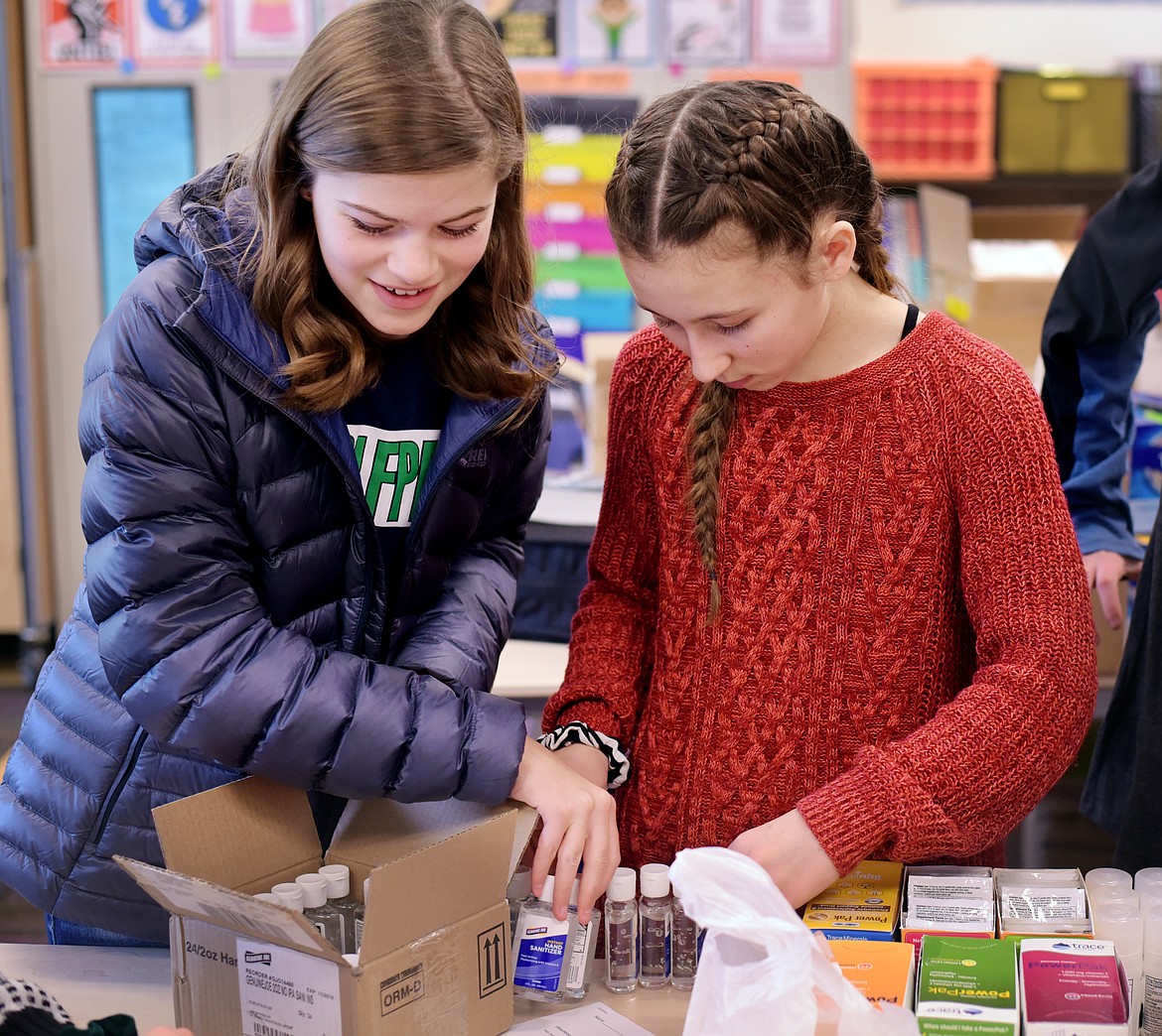 Sophia Nadasi, left, and Anastazia Loveless, both eighth-graders at West Valley School help with the assembly of &#147;dignity bags&#148; on Friday, Dec. 20. The bags are filled with information, personal care items, snacks and other useful things and will be given to members of the law enforcement community to give to anyone they believe could benefit from them. (Brenda Ahearn photos/Daily Inter Lake)