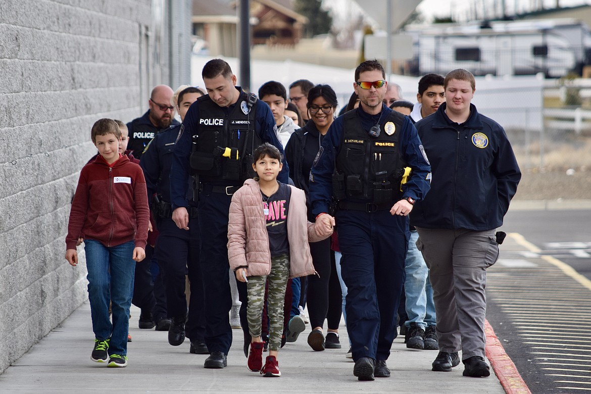 Charles H. Featherstone/Sun Tribune
Othello Police officers, Othello Police Explorers and kids walk toward Walmart on Saturday following a pizza lunch for the annual Shop With a Cop event.