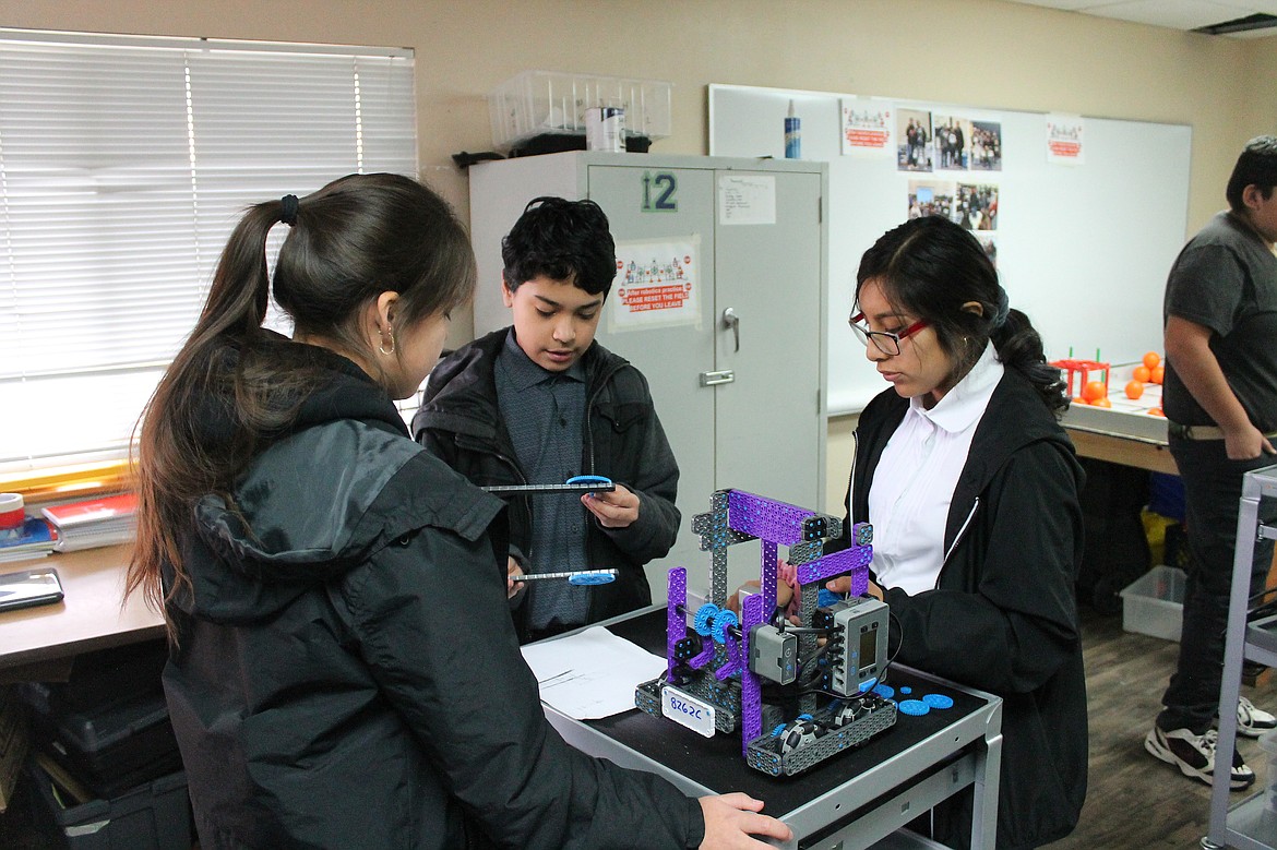 Rachal Pinkerton/Sun Tribune
(Left to right) Angela Santiago, Sergio Leon and Leslie De Los Santos work on modifying their robot. The team placed first in their first robotics competiton of the season.