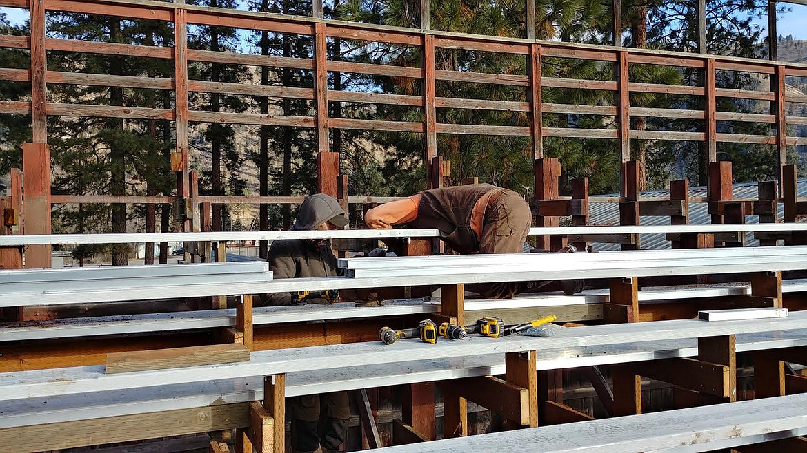 Two workers from MIH Construction, a Superior building contractor firm, work on seating at the Mineral County Rodeo arena. (Chuck Bandel/Mineral Independent)