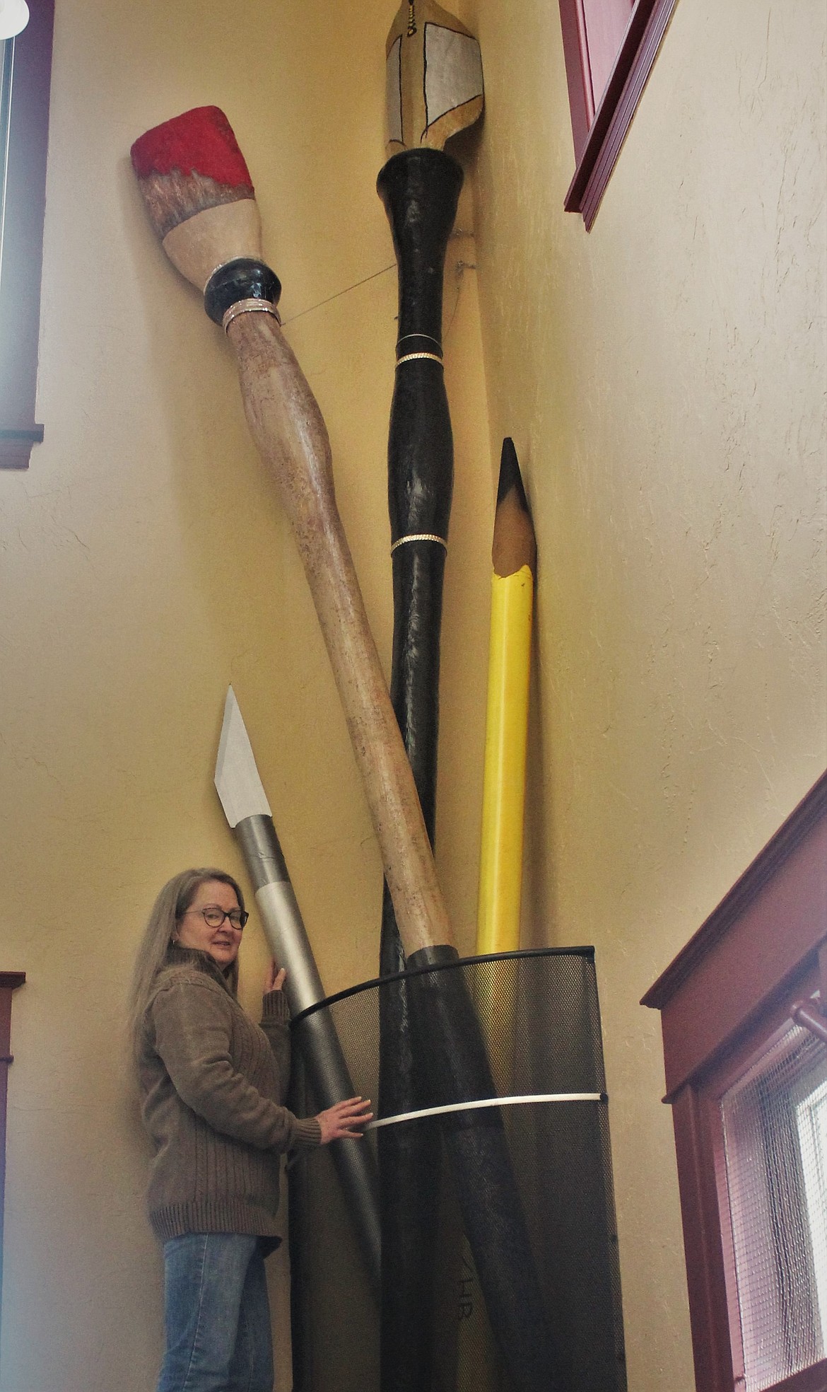 KATHLEEN HUBKA stands next to a new addition to the Paradise Center: a set of extremely tall art utensils in the stairwell. (John Dowd/Clark Fork Valley Press)