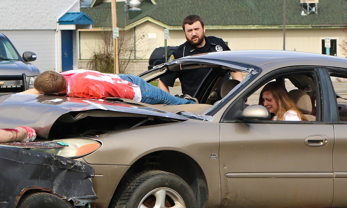 Photo by MANDI BATEMAN
Seth Bateman lies on the hood of the car, playing the part of a passenger who was killed in an accident caused by distracted driving, during the simulation put on by first responders for high school students on May 1.