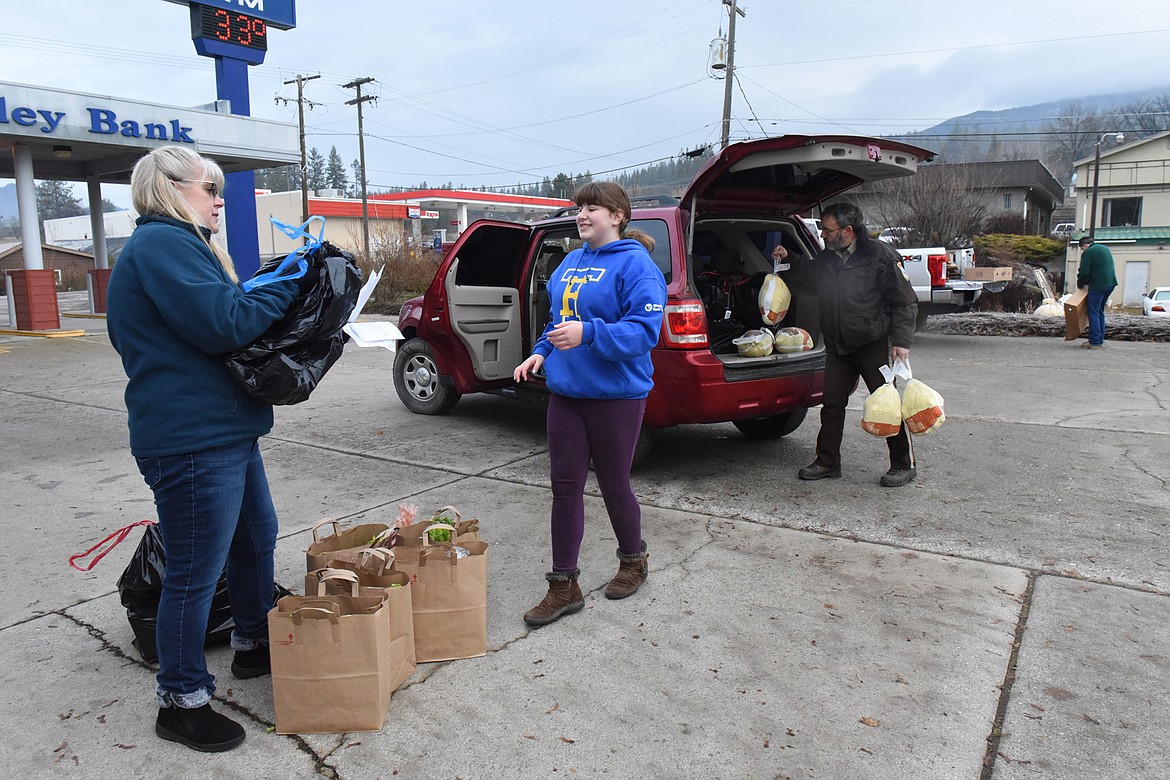 Tracy and Dakota Hensley make the handoff to Sheriff Tom Rummel, loading bags of gifts and food for families throughout Sanders County. (Carolyn Hidy/Valley Press)