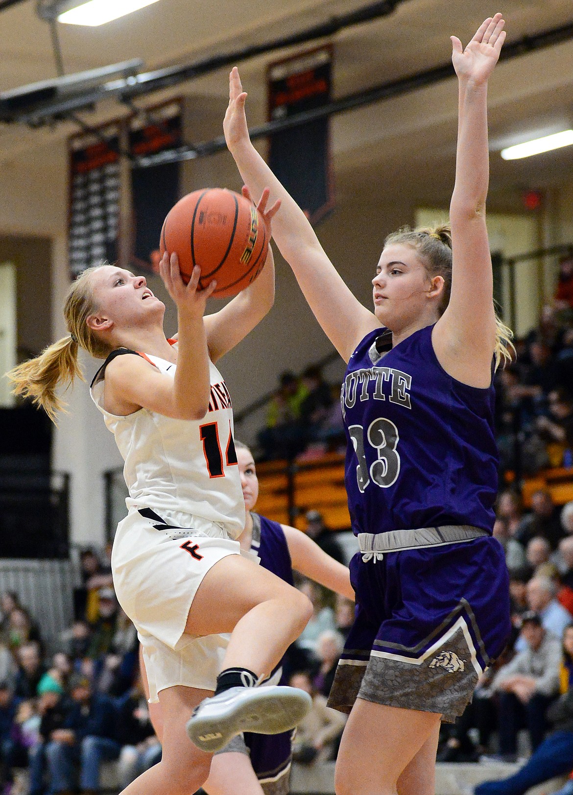 Flathead's Jenna Johnson (14) is fouled on her way to the basket by Butte's Ashley Olson (33) at Flathead High School on Friday. (Casey Kreider/Daily Inter Lake)