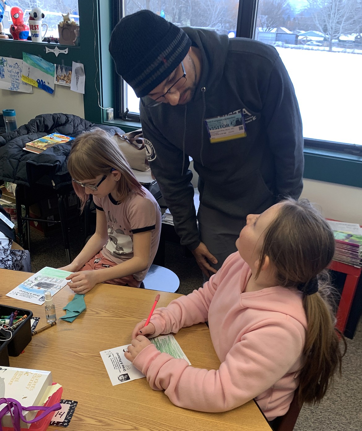 East Evergreen Elementary third-grader Jenasee Lolley, right, shares her drawing with AmeriCorps VISTA member Percival Field, while third-grader Braylynne Clarke continues to draw during Montana Campus Compact&#146;s &#147;MLK Read for Peace&#148; event on Thursday, Jan. 16. Students were asked to think about something they do to create fairness and equality, or their dream of a better world.