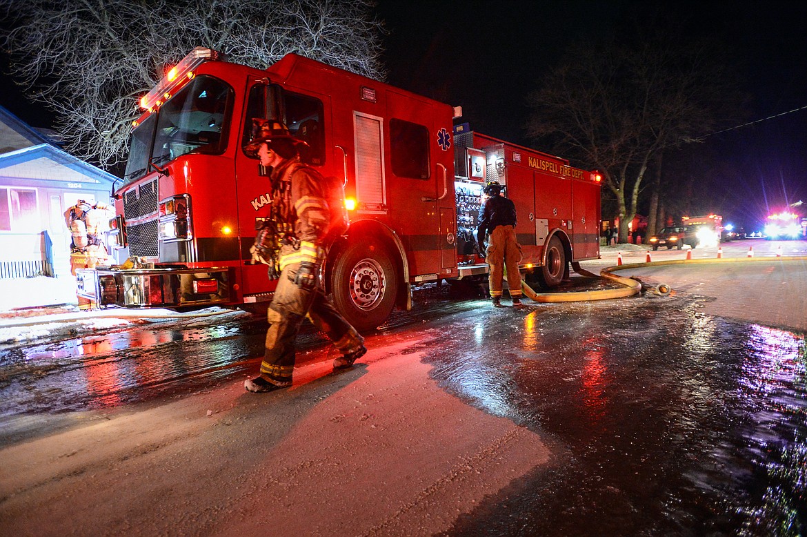 Water freezes on the snow-covered street as firefighters work at the scene of a house fire in the 1200 block of 4th Avenue East in Kalispell on Wednesday night. (Casey Kreider/Daily Inter Lake)