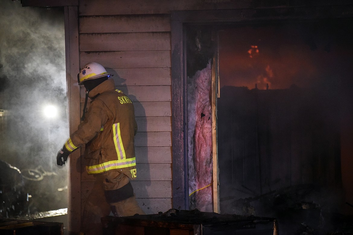 A firefighter works at the scene of a house fire in the 1200 block of 4th Avenue East in Kalispell on Wednesday night. (Casey Kreider/Daily Inter Lake)