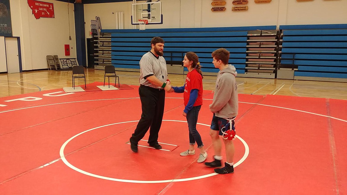 Local wrestling official Bobby Henderson shows his appreciation to Superior High School students Bailey Milender and Wesley Buchanan, members of the National Honor Society. The Society held a fundraiser prior to a recent match to support Henderson’s family. (Chuck Bandel/Mineral Independent)