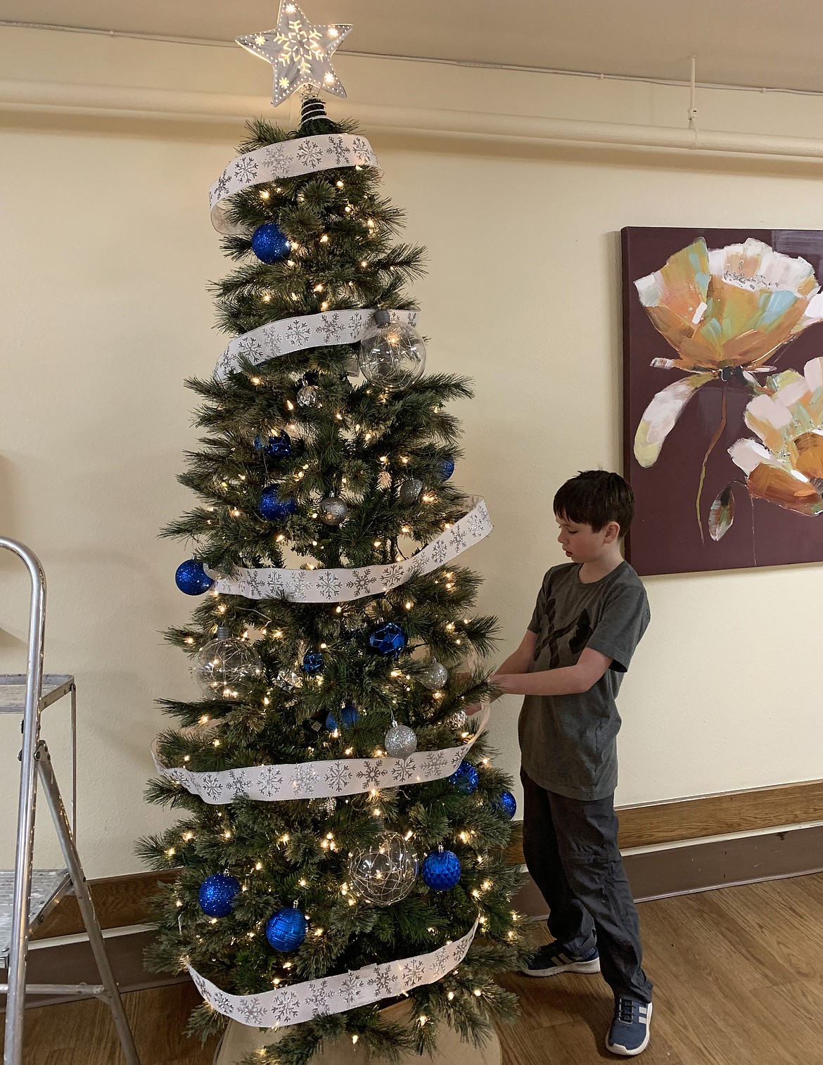 Logan Fisher, 12, of Boy Scout Troop 8202, carefully hangs ornaments on a tree in Coeur d'Alene of Cascadia Health on Thanksgiving night. Logan grossed $15,000 in popcorn sales last fall and used $1,200 of it to buy decorations for the senior facility that was in need of Christmas cheer. (Courtesy photo)