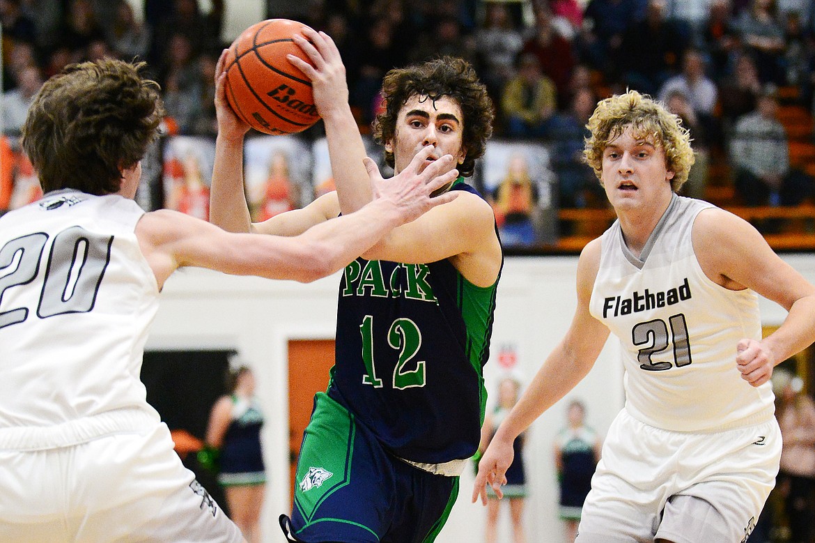 Glacier's Weston Price (12) heads to the hoop between Flathead's Cooper Smith (20) and Ethan Vandenbosch (21) during a crosstown matchup at Flathead High School on Friday. (Casey Kreider/Daily Inter Lake)