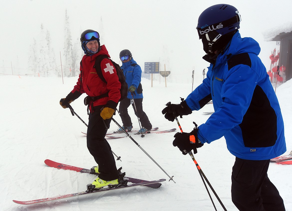 Whitefish Mountain Resort ski patroller Brenda Guzman smiles at Bill Cubbage as she skis away from the patrol office on the summit of Big Mountain.