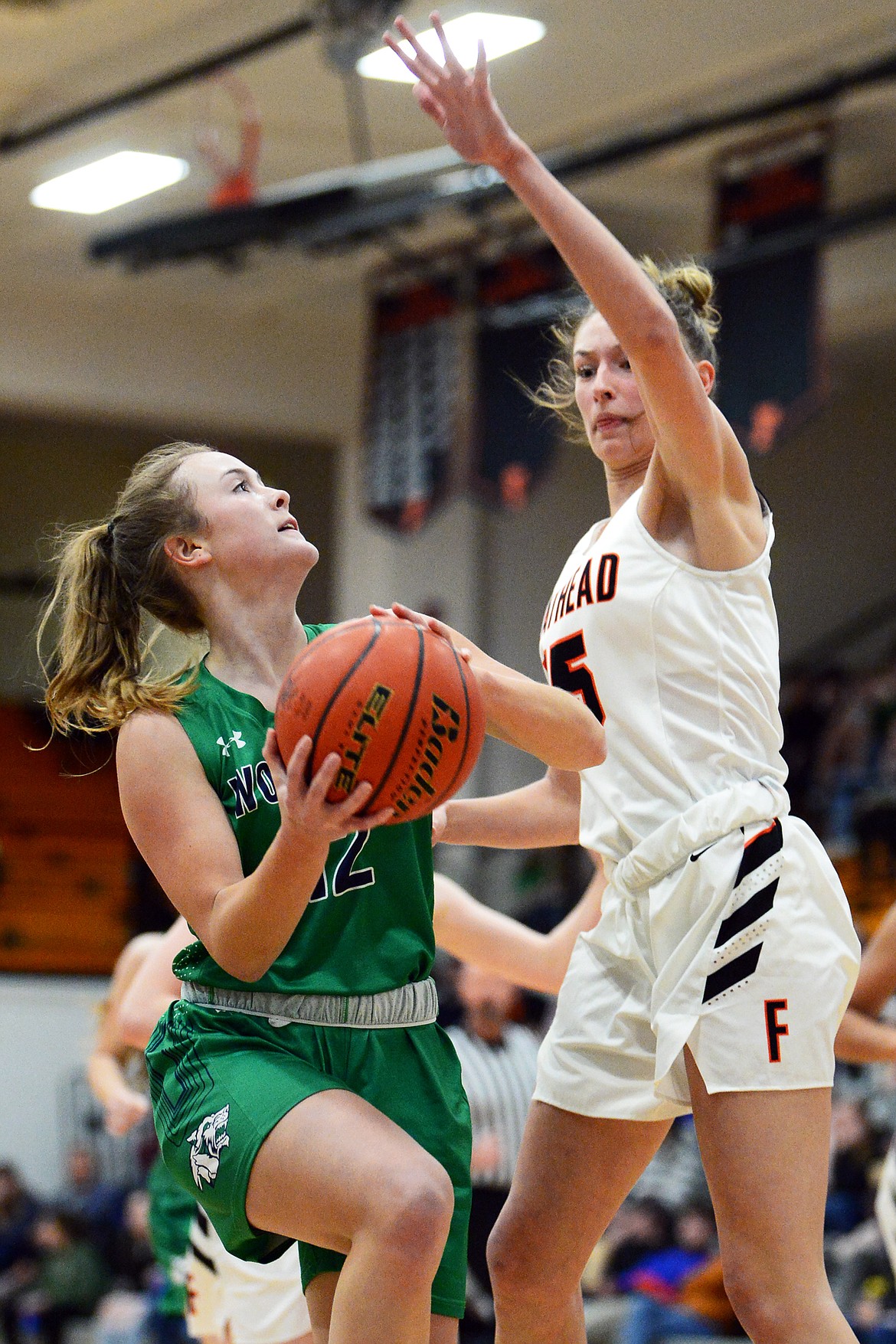 Glacier's Kenzie Williams (12) drives to the basket guarded by Flathead's Clare Converse (15) in the first half during a crosstown matchup at Flathead High School on Thursday. (Casey Kreider/Daily Inter Lake)