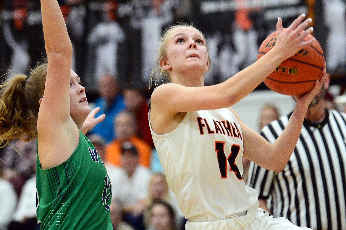 Flathead's Jenna Johnson (14) drives to the basket past Glacier's Kenzie Williams (12) during a crosstown matchup with Glacier at Flathead High School on Thursday. (Casey Kreider/Daily Inter Lake)