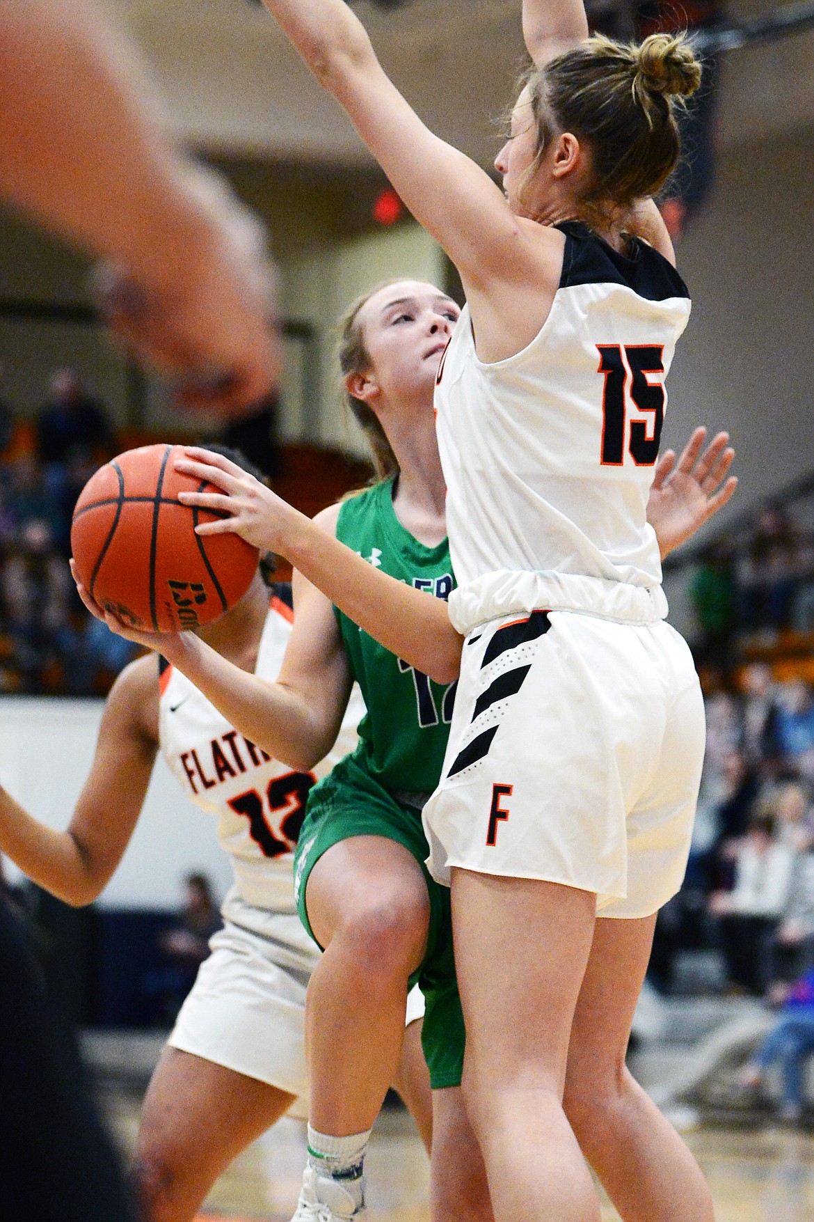 Glacier's Kenzie Williams (12) drives to the basket guarded by Flathead's Clare Converse (15) during a crosstown matchup at Flathead High School on Thursday. (Casey Kreider/Daily Inter Lake)