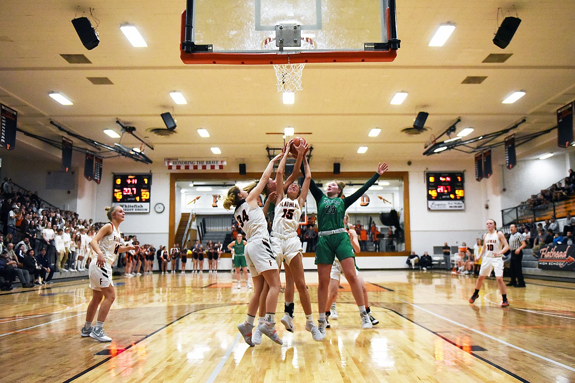 Flathead's Molly Winters (34) and Clare Converse (15) battle Glacier's Aubrie Rademacher (14) and Emma Anderson (25) for a rebound in the last minute of play during a crosstown matchup at Flathead High School on Thursday. Glacier won, 51-49. (Casey Kreider/Daily Inter Lake)