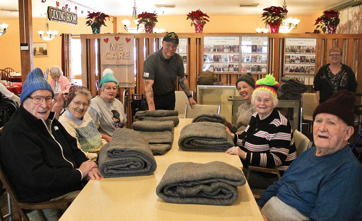 Photo by TONIA BROOKS
Tom Cheney at the head of the table handed out warm blankets and homemade knitted hats to the residents of the Restorium who had served in the capacity of first responder or with the armed forces. 

Next to Cheney (a US AIRFORCE veteran), on the right (and travelling clockwise) is Rosemary Hopkins (US NAVY), Lois Frazier (Police Dept. Dispatcher), Don Dozier (US NAVY), Selby Sharp (US ARMY), Carol Pomeroy (V.A. Nurse), and Bunny Bennett (EMT). 

Not pictured, though also receipents, were: Rudy Costanzo (US MARINE CORPS), Bill McClive (US ARMY), and Warren Scott (US ARMY).