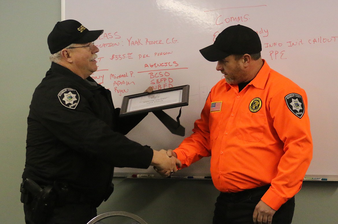 Photo by MANDI BATEMAN 
Boundary Search and Dive Rescue Team Director Levi Falck receives a rescue award and Sheriff&#146;s Office challenge coin from Boundary County Sheriff Dave Kramer.