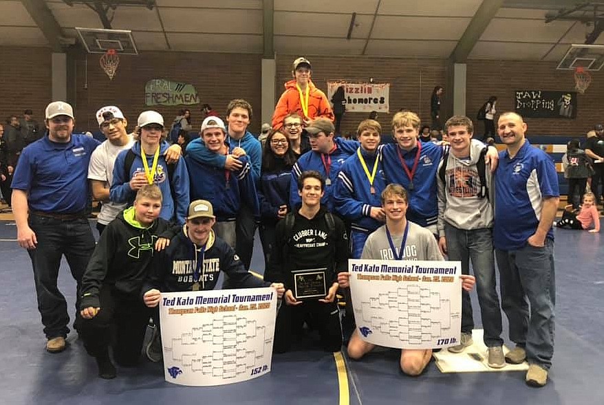 The 2020 Ted Kato team champion Mission-Charlo Bulldogs pose with their first place plaque. Perched atop shoulders: (103) Kody Dillard (4th).Back row (standing): coach Jake Bosley, Robert Dempsey, (120) Isaiah Fields (4th), (126) Walker Murphy (2nd), George Ranney, Gracie DuMontier (manager), (152B) Christian Smith (3rd), (205) Miles Anderson (2nd), (132) Canyon Sargent (4th), (160) Ethan Diaz (2nd), Charley Adams, head coach Lyle Cronk.Front row (kneeling): Chance Bockman , (152) Darwin Adams (1st), Isaac DuMontier (holding plaque), (170) Isaiah Allik (1st). Photo courtesy of Daisy Adams