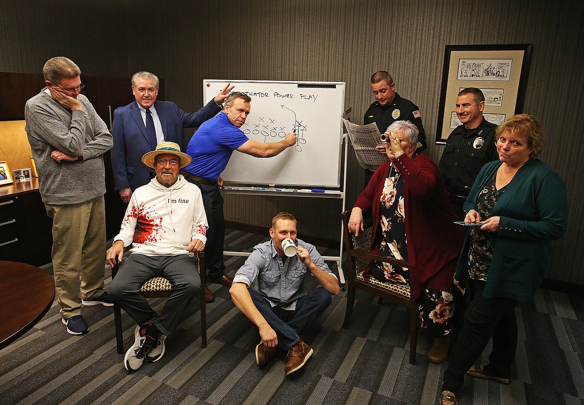 Jim Hightower has fun with other members of the Press Pigskin Prognosticators in Press Managing Editor Mike Patrick's office during the 2019-20 football season. The community is mourning the loss of Hightower, who died Sunday. From left: Jim Winger, Hightower, Steve Cameron (seated), Mike Randles, Jared Staples (seated and sipping), retired Post Falls Police Chief Pat Knight (reading), Suzanna Spencer (spying), Coeur d'Alene Police Chief Lee White (laughing) and Anne Hagman (smirking).