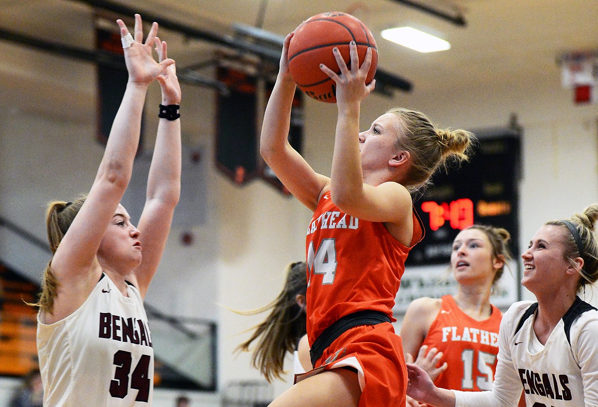 Flathead's Jenna Johnson (14) drives to the basket between Helena High defenders Caroline Bullock (34) and McKayla Kloker (21) at Flathead High School on Saturday. (Casey Kreider/Daily Inter Lake)