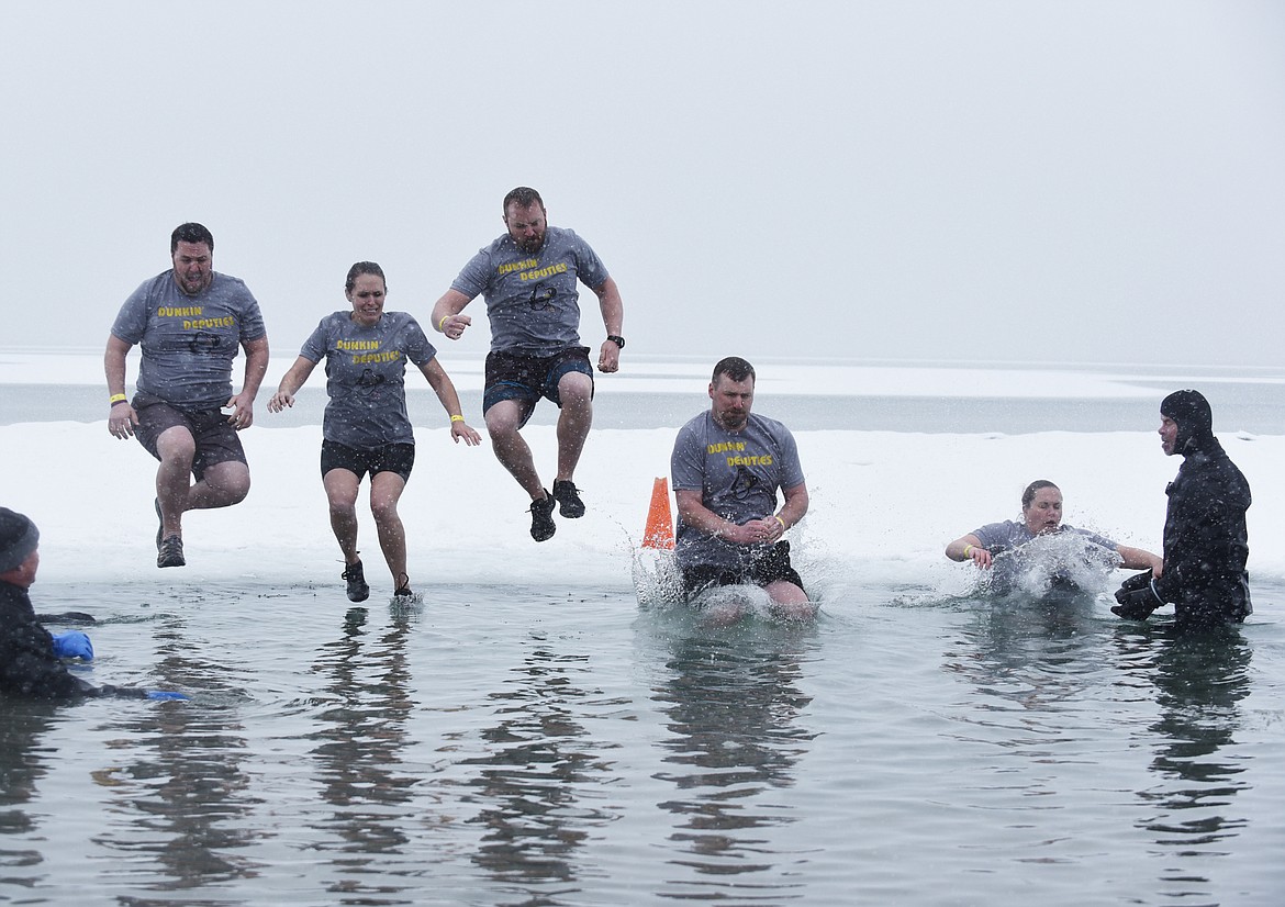 A group from the Flathead County Sheriff's Office jumps into Whitefish Lake Saturday morning during the annual Penguin Plunge at City Beach. The event raises money for Special Olympics Montana. (Heidi Desch/Whitefish Pilot)