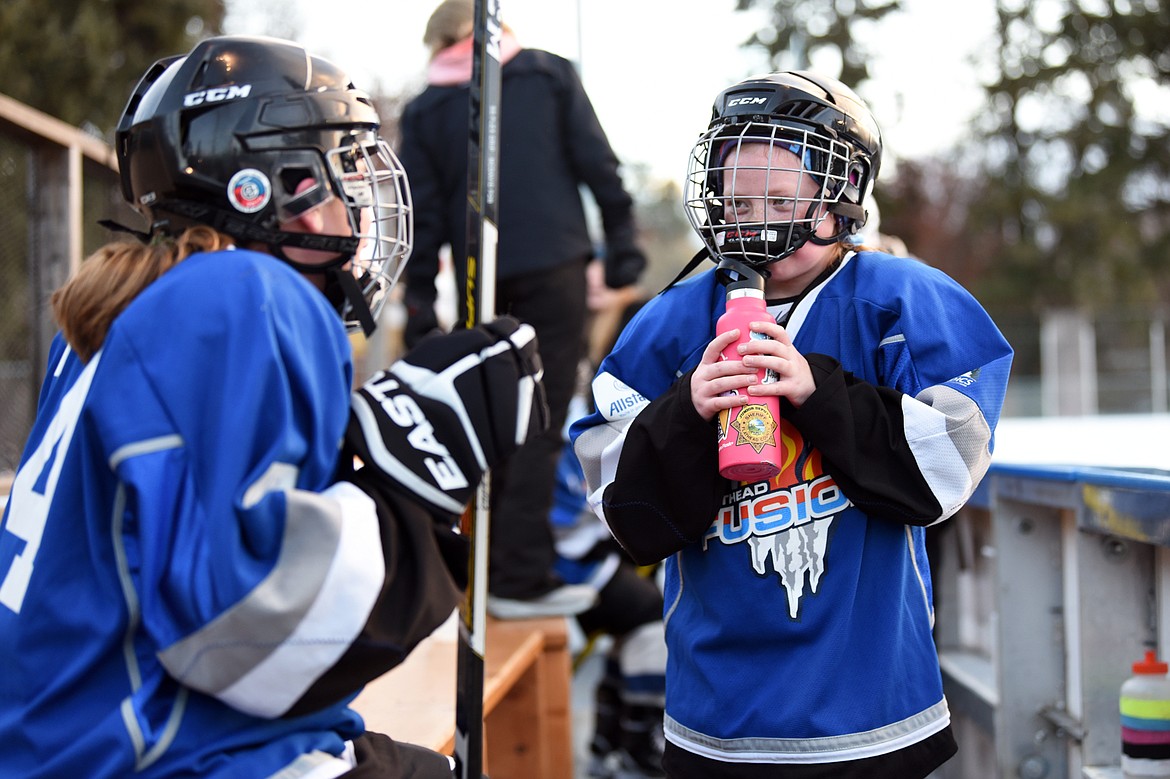 Addisen Crofts, right, gets a drink of water through her facemask as she talks with team captain Charlotte &#147;Charley&#148; Wallace as they play the Lethbridge Cyclones during the 14U Girls Winter Classic 2020 at the Woodland Ice Center in Kalispell on Friday. (Casey Kreider/Daily Inter Lake)