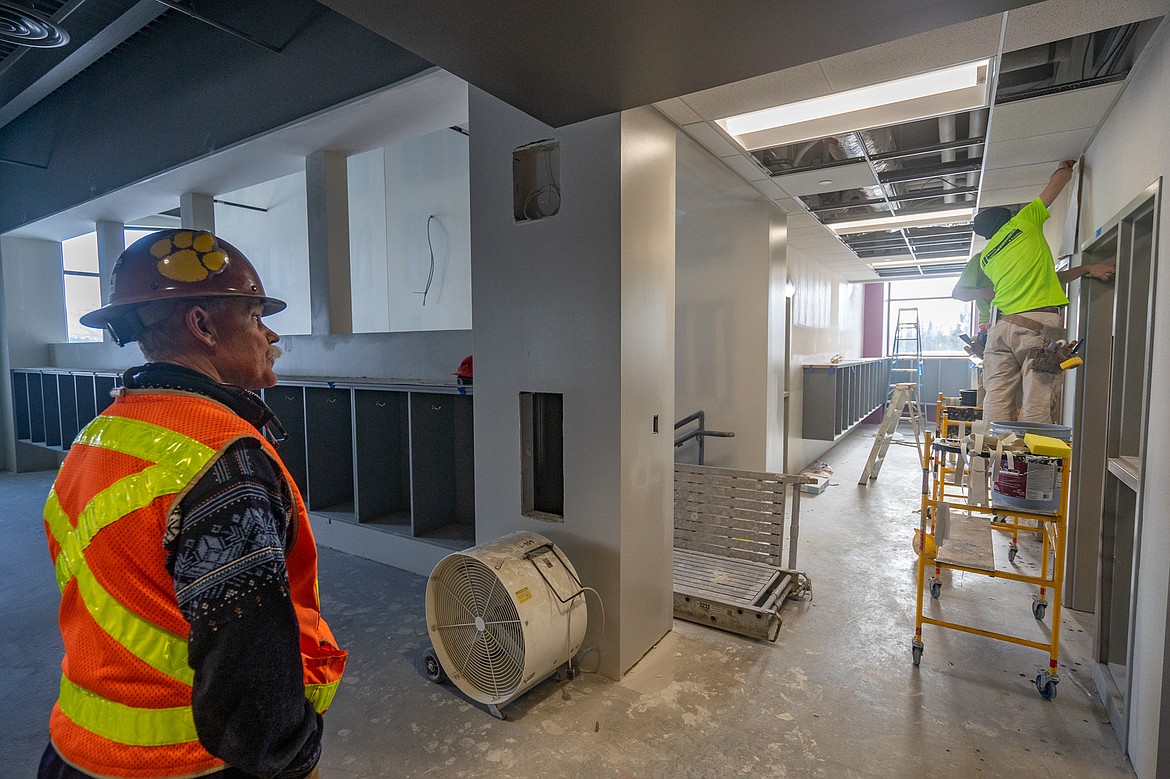 Dow Powell, Whitefish School District's owner's representative on the Muldown Elemnetary construction project, watches a pair of workers install wallpaper in the fourth-grade wing of the new elementary school. (Daniel McKay/Whitefish Pilot)