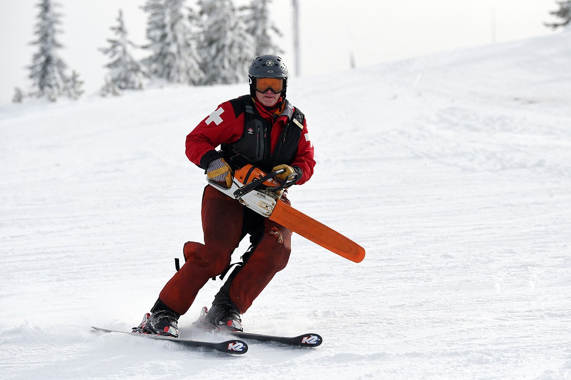 Ski patroller Dave Filler totes a chainsaw as he heads down a run to perform some tree work at Blacktail Mountain Ski Area.