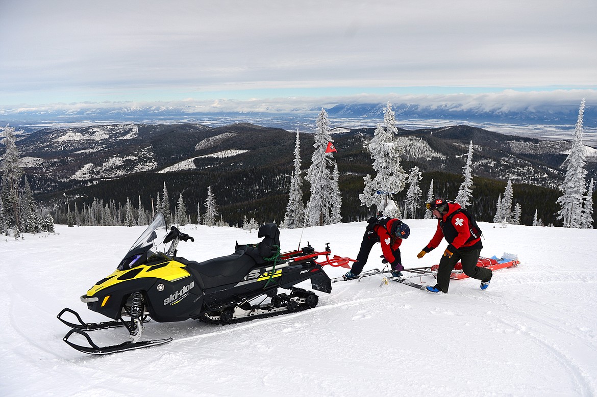 Colyne Hislop and Camas Garnett demonstrate attaching a rescue toboggan to the back of a snowmobile for a potential rescue.