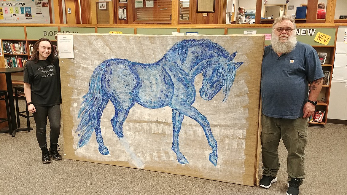 Plains artist Dave Williams and his protege Haylee Steinebach, a Plains High sophomore, display their painting in the Plains High library. (Chuck Bandel/Valley Press)