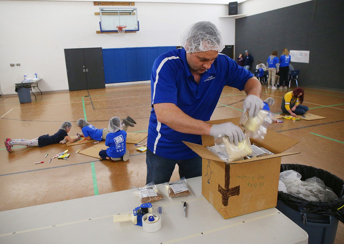 North Idaho Christian School parent John Pilgrim packs bags of food during the school's Feed the Need packing party. (LOREN BENOIT/Press)