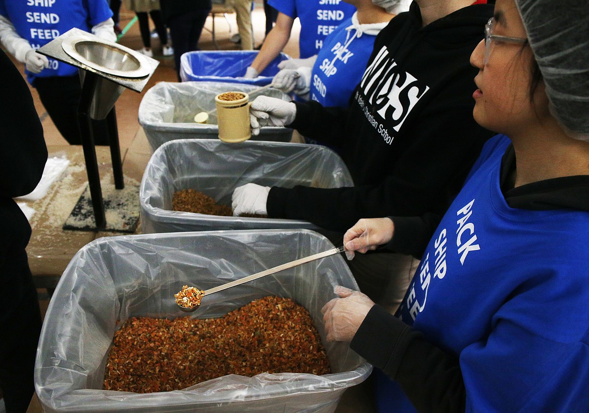 Sophomore Melanie Gabrielson, right, waits to pour a serving of dried vegetables into a bag during a Feed the Need packing party at North Idaho Christian School. (LOREN BENOIT/Press)