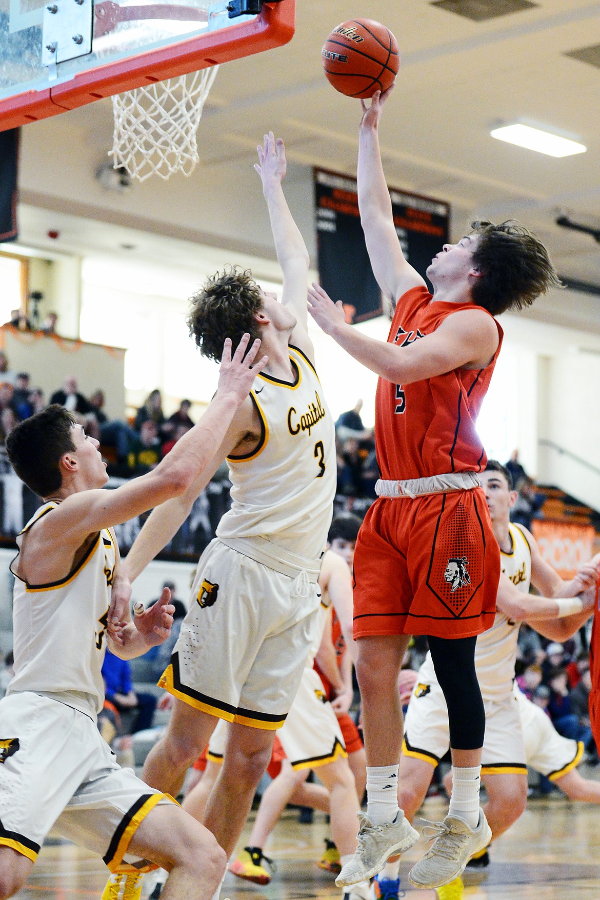 Flathead's Tannen Beyl (5) goes to the hoop against Helena Capital's Ryan Quinn (3) and Trevor Swanson (5) at Flathead High School on Saturday. (Casey Kreider/Daily Inter Lake)